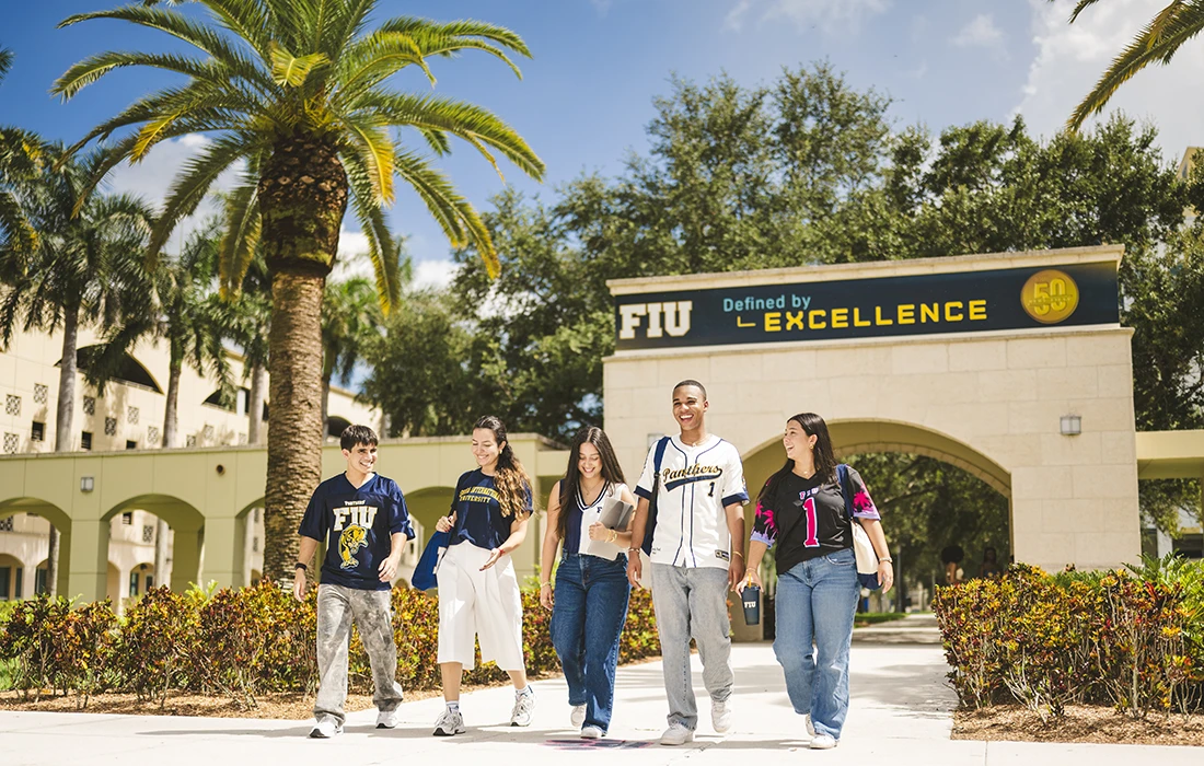 FIU students walk under the Excellence sign